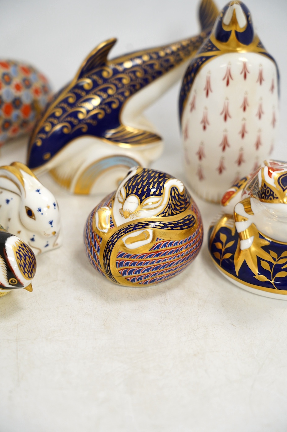 Eight Royal Crown Derby porcelain paperweights in the form of animals including a penguin, rabbit and seal, largest 17cm wide. Condition - seven good, one broken